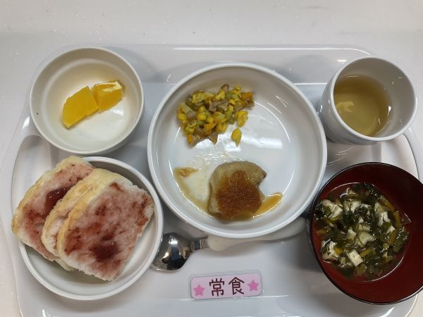 《常食》給食は米粉パン　かじきのステーキ　コーンと人参入りアスパラソテー　すまし汁　オレンジです。
